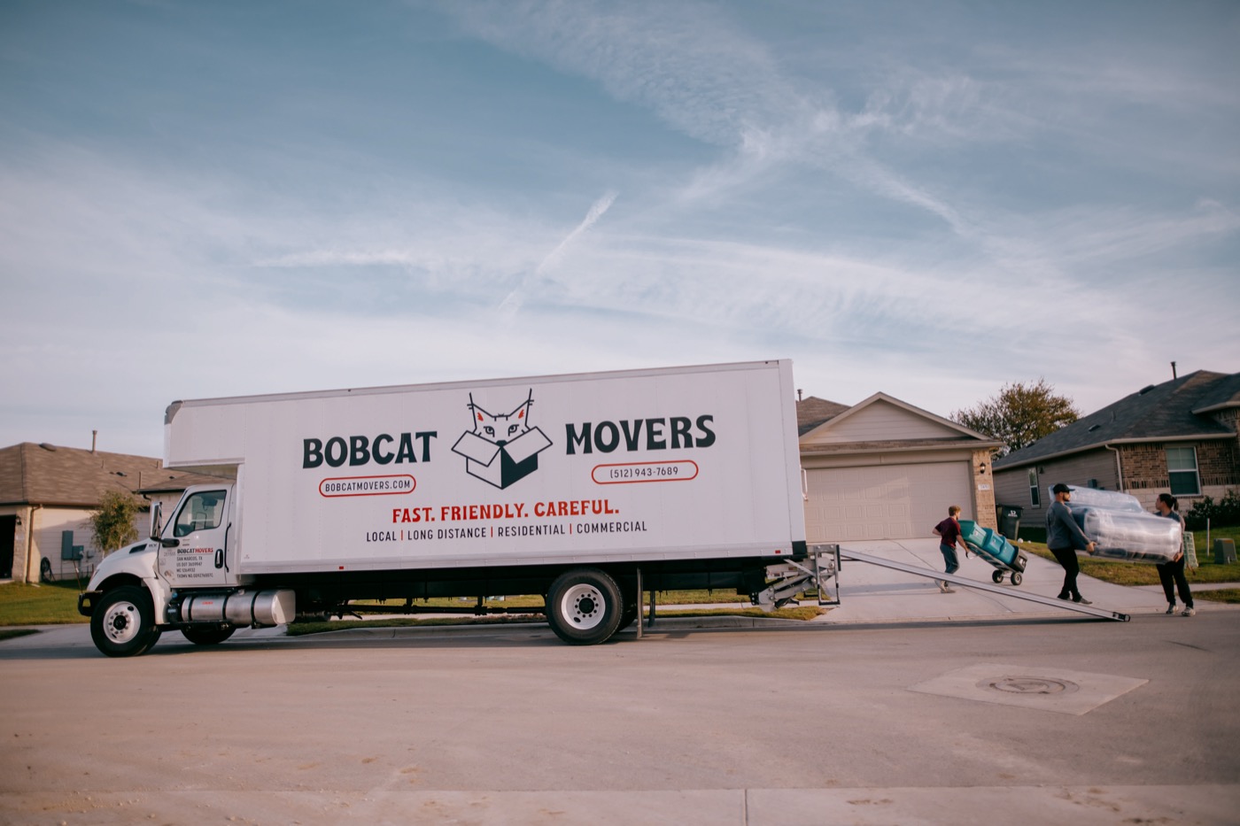 Bobcat Movers crew loading a branded box truck on a Texas Hill Country street